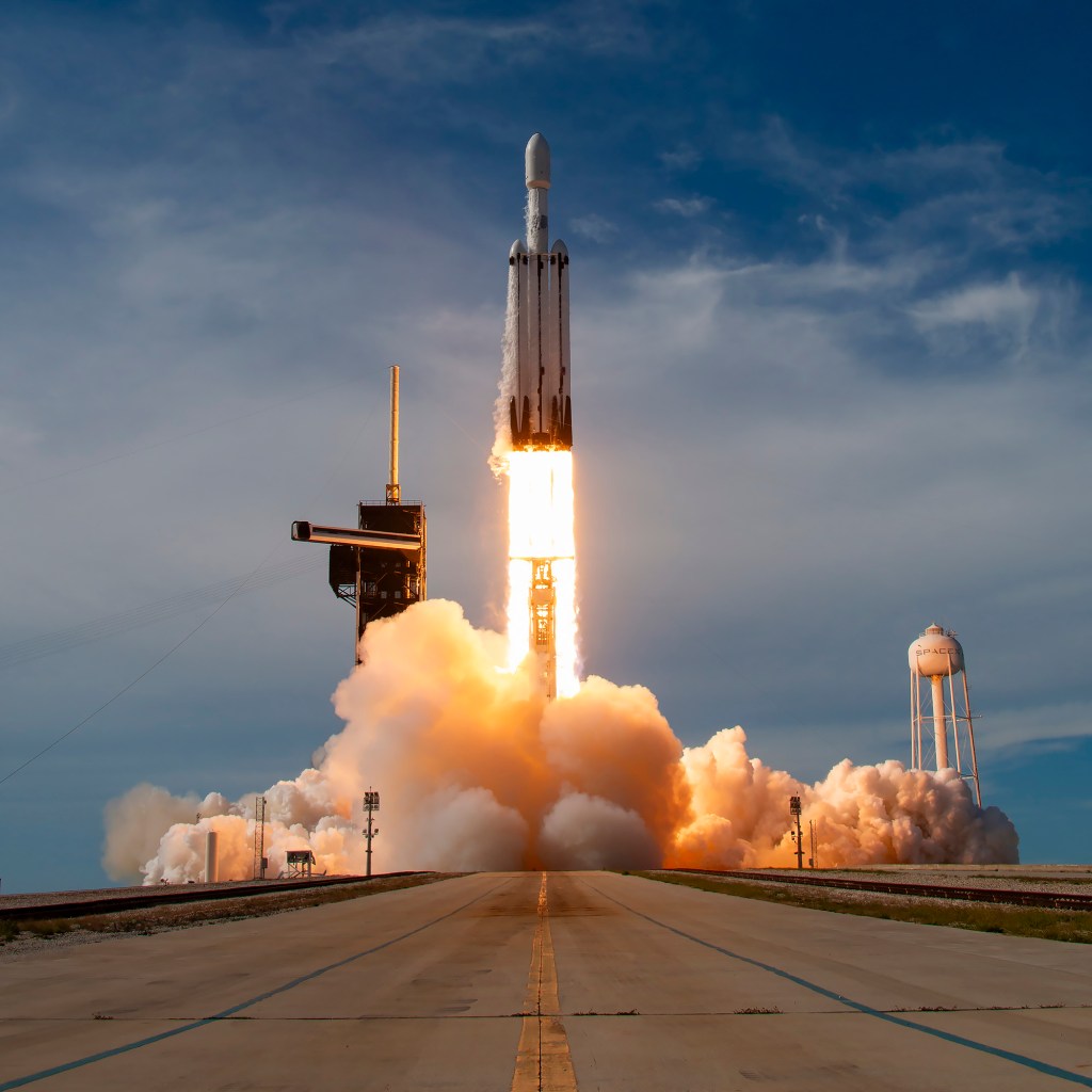 A rocket launch from the launch pad with the strong perspective of the rocket "rollout" road leading the eye right to the cloud of smoke and flame bursting from the launching rocket.